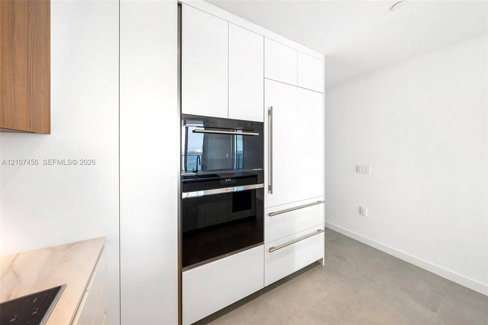 1400 Biscayne Boulevard, #2604, Miami, Miami, FL 33132 Floor-to-ceiling white cabinetry with integrated panel-ready refrigerator, built-in wall oven, matte stainless steel hardware, and large-format tile flooring