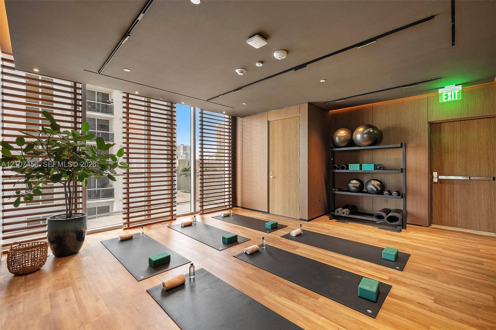 1400 Biscayne Boulevard, #2604, Miami, Miami, FL 33132 Fitness studio featuring wood-finish flooring, floor-to-ceiling windows with horizontal wood-slat privacy screens, and integrated recessed ceiling lighting