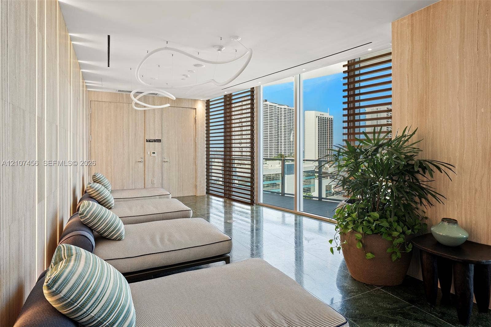 1400 Biscayne Boulevard, #2604, Miami, Miami, FL 33132 Floor-to-ceiling windows with horizontal louvered screens, natural wood-finish wall paneling, integrated recessed LED accent lighting, contemporary sculptural overhead light fixture, and polished stone flooring