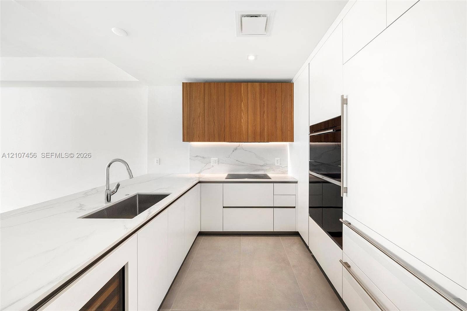 1400 Biscayne Boulevard, #2604, Miami, Miami, FL 33132 Kitchen featuring white flat-panel cabinetry, contrasting wood-finish upper cabinets, stone-surfaced countertops, integrated appliances, and under-cabinet lighting