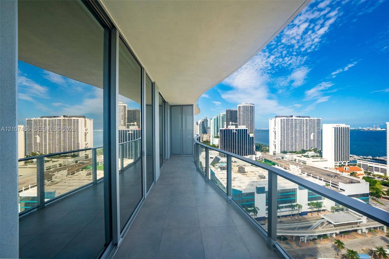 1400 Biscayne Boulevard, #2604, Miami, Miami, FL 33132 Curved private balcony featuring large-format tile flooring, a glass-panel railing, and full-height floor-to-ceiling glass sliding doors