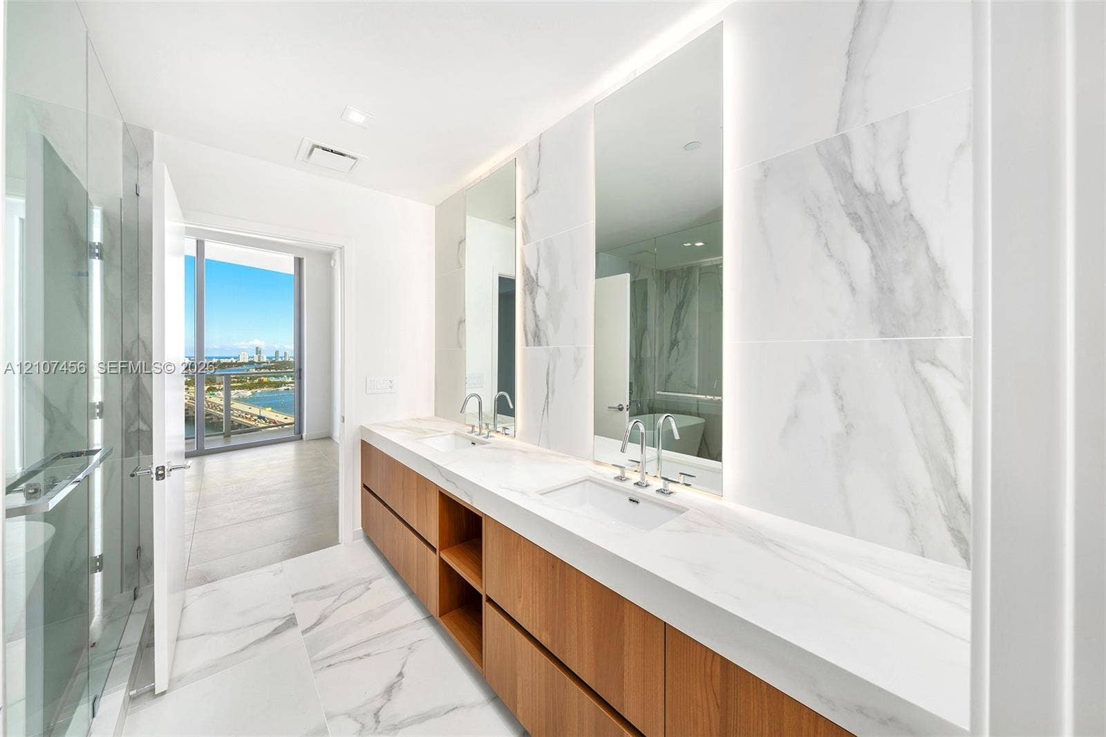 1400 Biscayne Boulevard, #2604, Miami, Miami, FL 33132 Dual-sink vanity with wood-finish cabinetry, solid surface countertops, floor-to-ceiling porcelain tile, integrated LED-lit mirrors, and a glass-enclosed shower