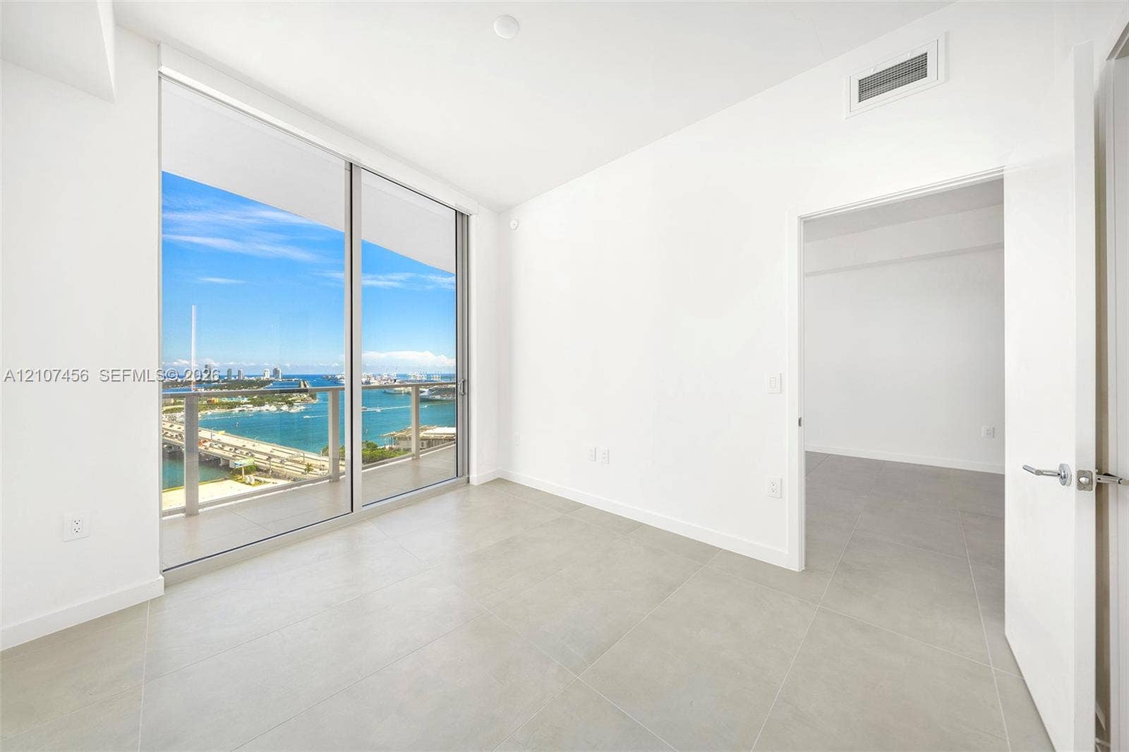 1400 Biscayne Boulevard, #2604, Miami, Miami, FL 33132 Floor-to-ceiling sliding glass doors, private balcony, large format tile flooring, and panoramic water and cityscape scenery