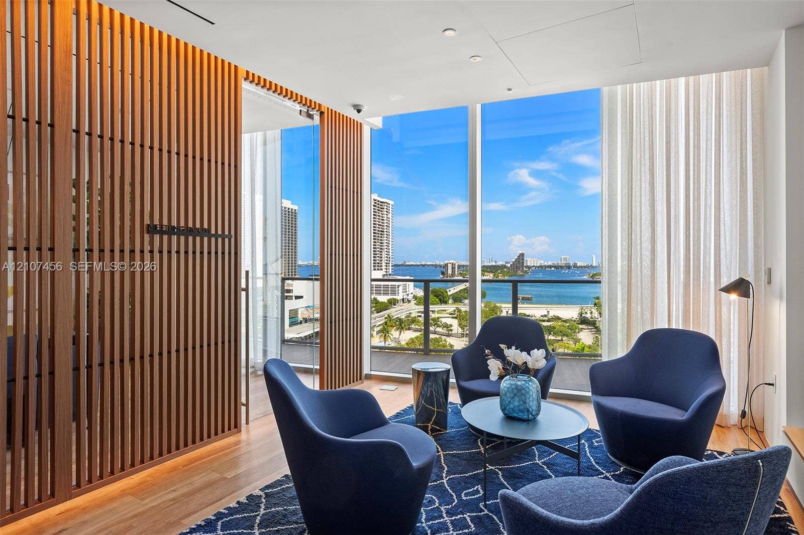 1400 Biscayne Boulevard, #2604, Miami, Miami, FL 33132 Floor-to-ceiling windows, vertical wood-slat privacy screening, recessed lighting, and a glass-railing balcony featuring a coastal waterfront backdrop
