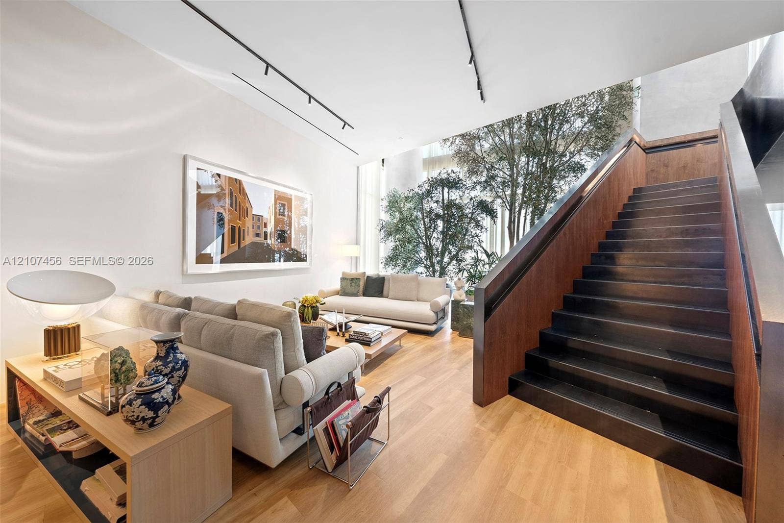 1400 Biscayne Boulevard, #2604, Miami, Miami, FL 33132 Open-concept interior featuring tall ceilings, wood-finish flooring, a dark-toned floating staircase, and floor-to-ceiling glass panels