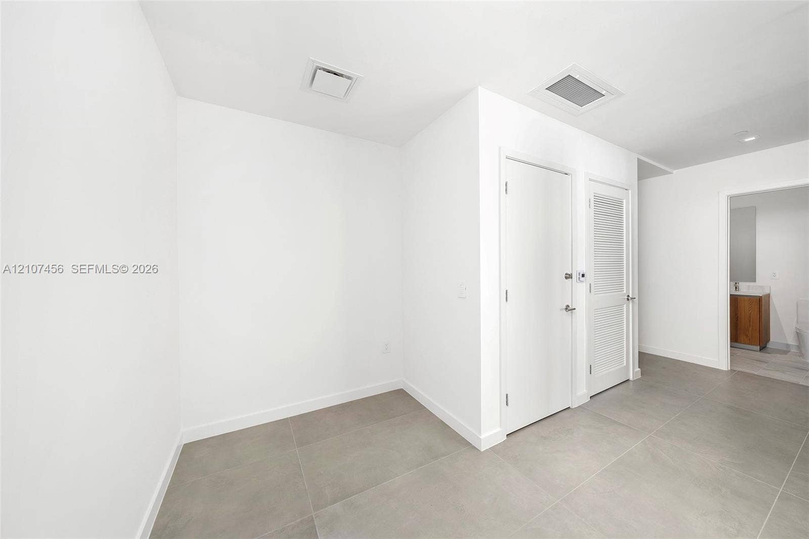 1400 Biscayne Boulevard, #2604, Miami, Miami, FL 33132 Interior space featuring large-format tile flooring, crisp white walls, solid-core interior doors, and a louvered closet door