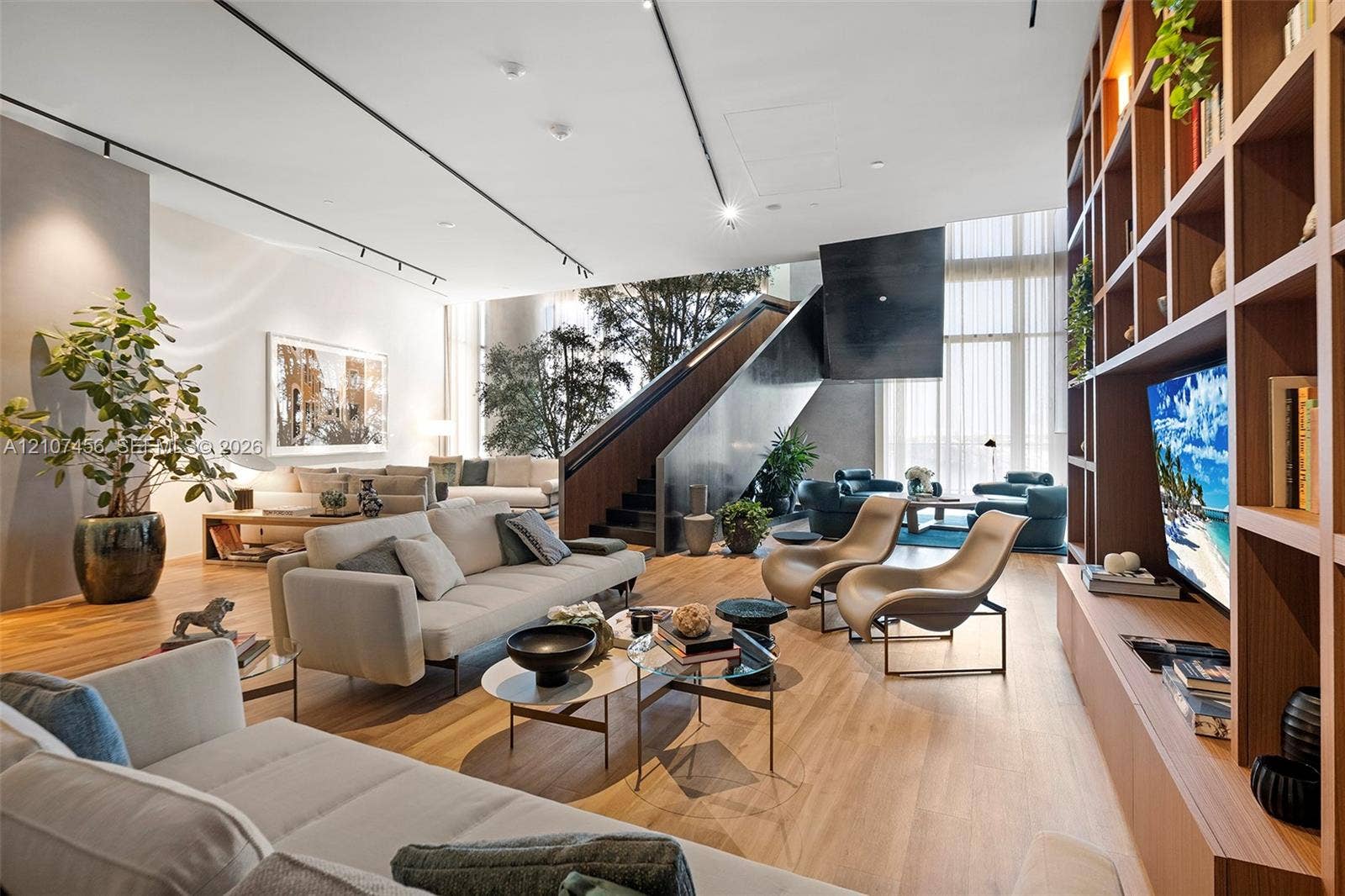 1400 Biscayne Boulevard, #2604, Miami, Miami, FL 33132 Open-concept living space featuring wood-finish flooring, floor-to-ceiling windows, custom built-in wooden shelving, a dramatic sculptural staircase, and ceiling-mounted track lighting