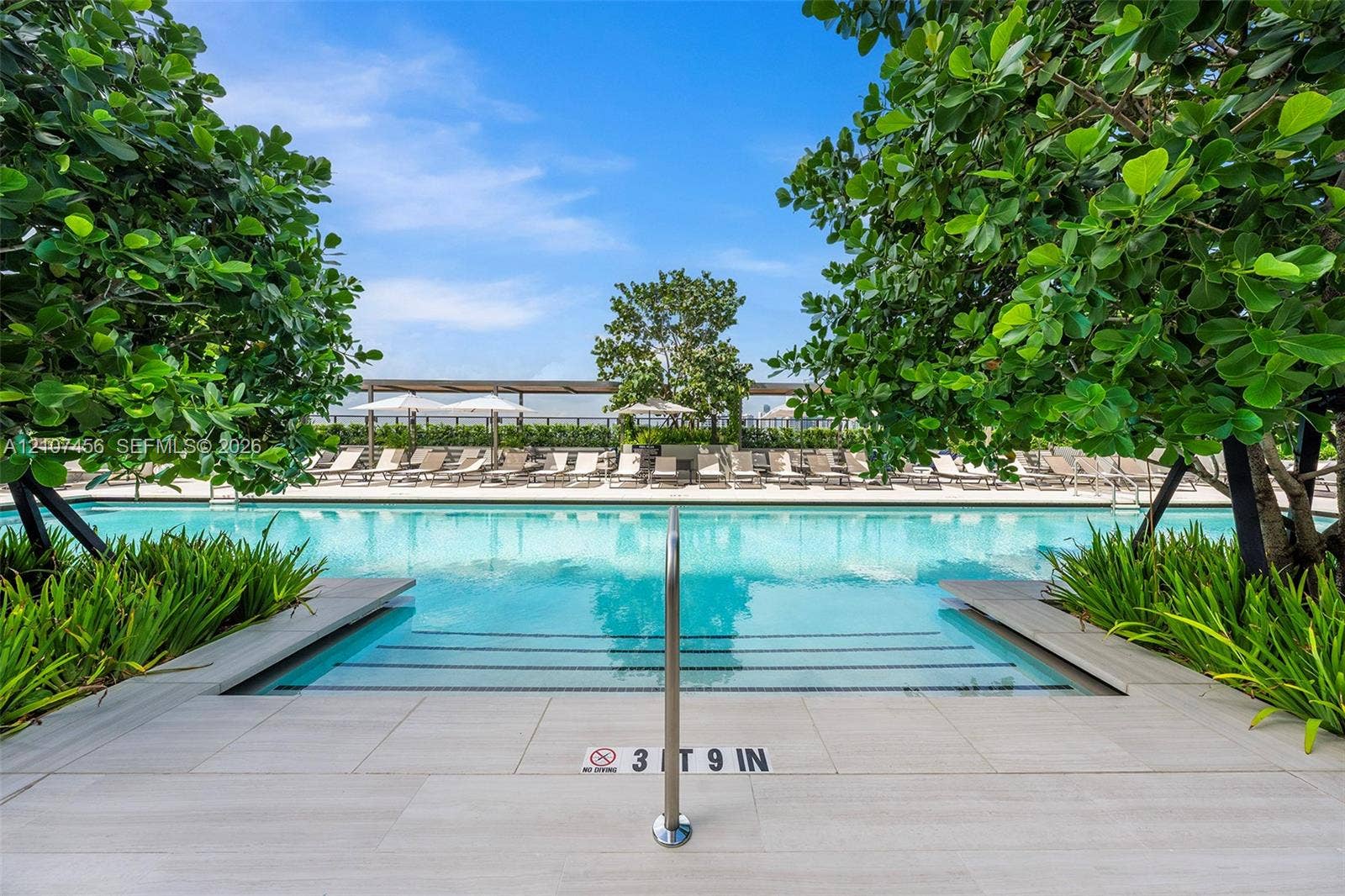 1400 Biscayne Boulevard, #2604, Miami, Miami, FL 33132 Swimming pool with stone-finish decking, stainless steel handrail, integrated steps, and surrounding mature landscaping