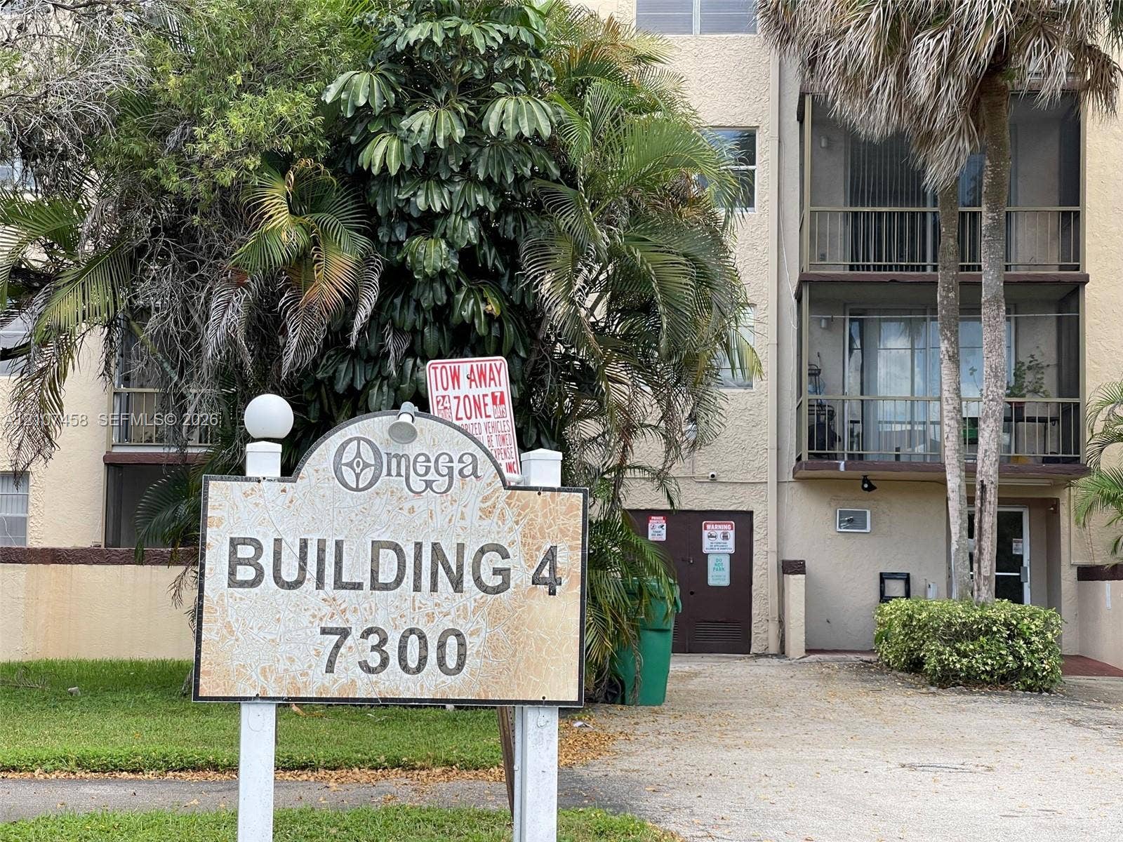 7300 NW 17th Street, #421, Plantation, Plantation, FL 33313 Multi-story building featuring stucco exterior, screened balconies, and mature palm landscaping