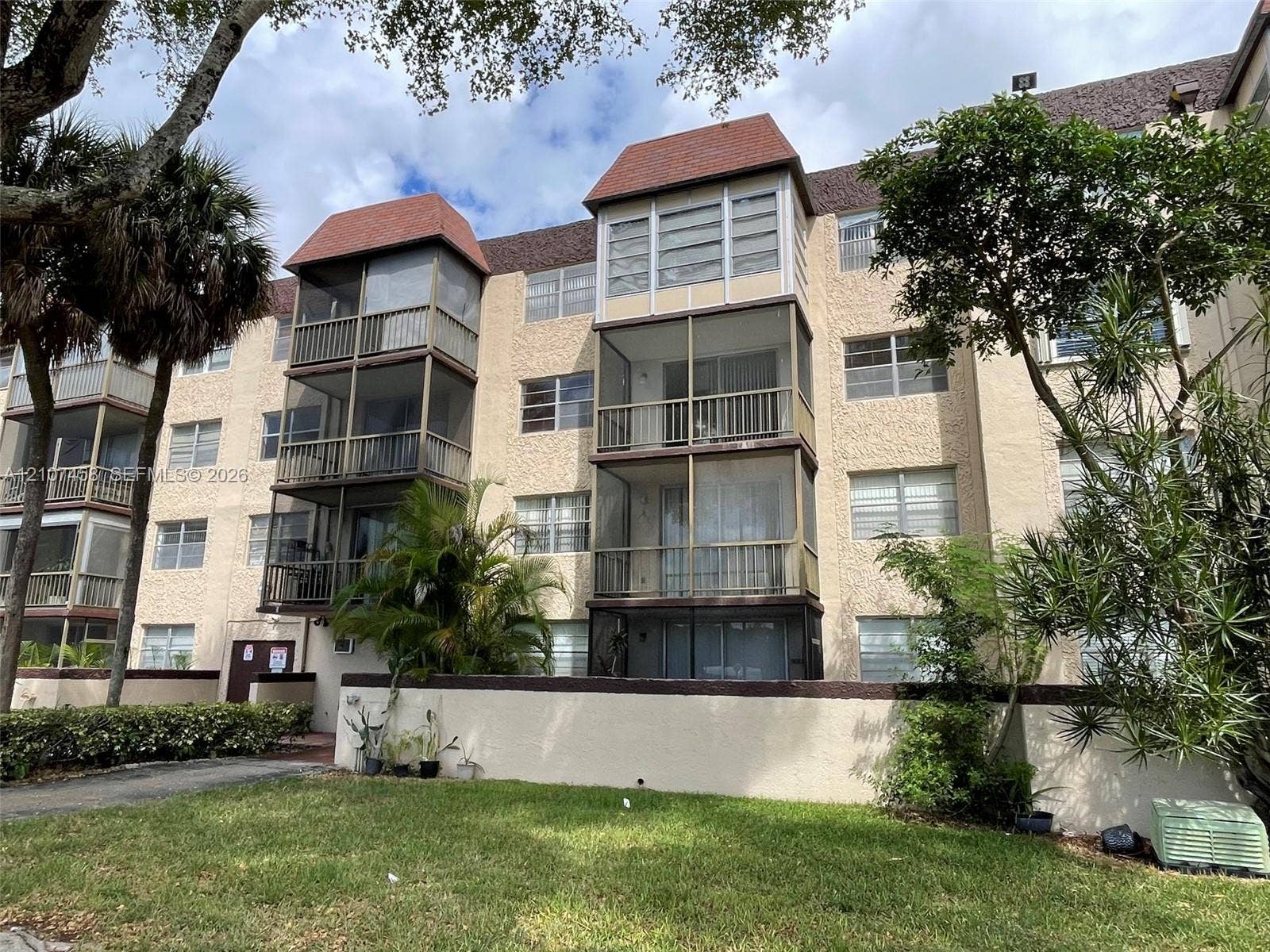 7300 NW 17th Street, #421, Plantation, Plantation, FL 33313 Multi-story residential building featuring textured stucco exterior, shingled mansard rooflines, and multiple screened-in balconies