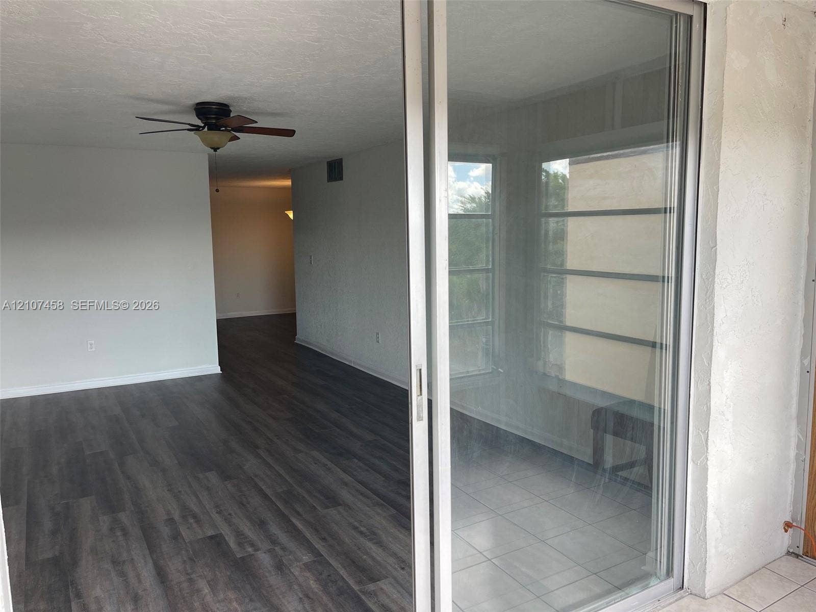 7300 NW 17th Street, #421, Plantation, Plantation, FL 33313 Sliding glass door entry featuring wood-finish flooring, a ceiling fan with integrated lighting, and tile flooring on the enclosed patio