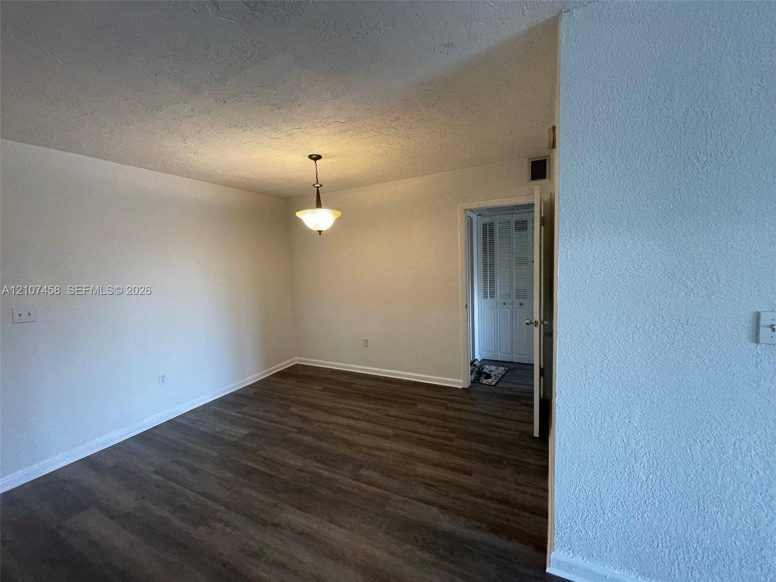 7300 NW 17th Street, #421, Plantation, Plantation, FL 33313 Room featuring wood-finish flooring, a neutral color palette, a classic pendant light fixture, and a doorway leading to a storage closet with louvered doors