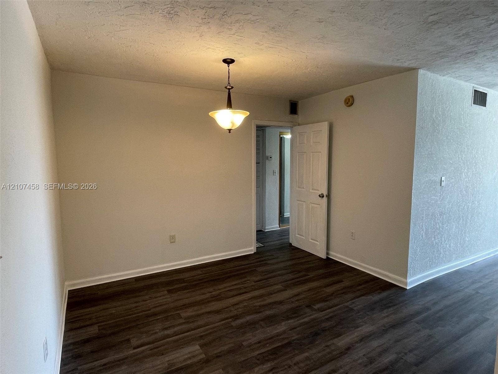 7300 NW 17th Street, #421, Plantation, Plantation, FL 33313 Wood-finish flooring, textured ceiling, and hanging pendant light fixture with a multi-panel interior door