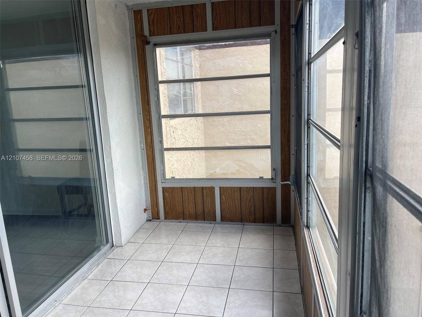 7300 NW 17th Street, #421, Plantation, Plantation, FL 33313 Enclosed porch featuring ceramic tile flooring, wood-panel wall accents, horizontal sliding windows, and a glass sliding door