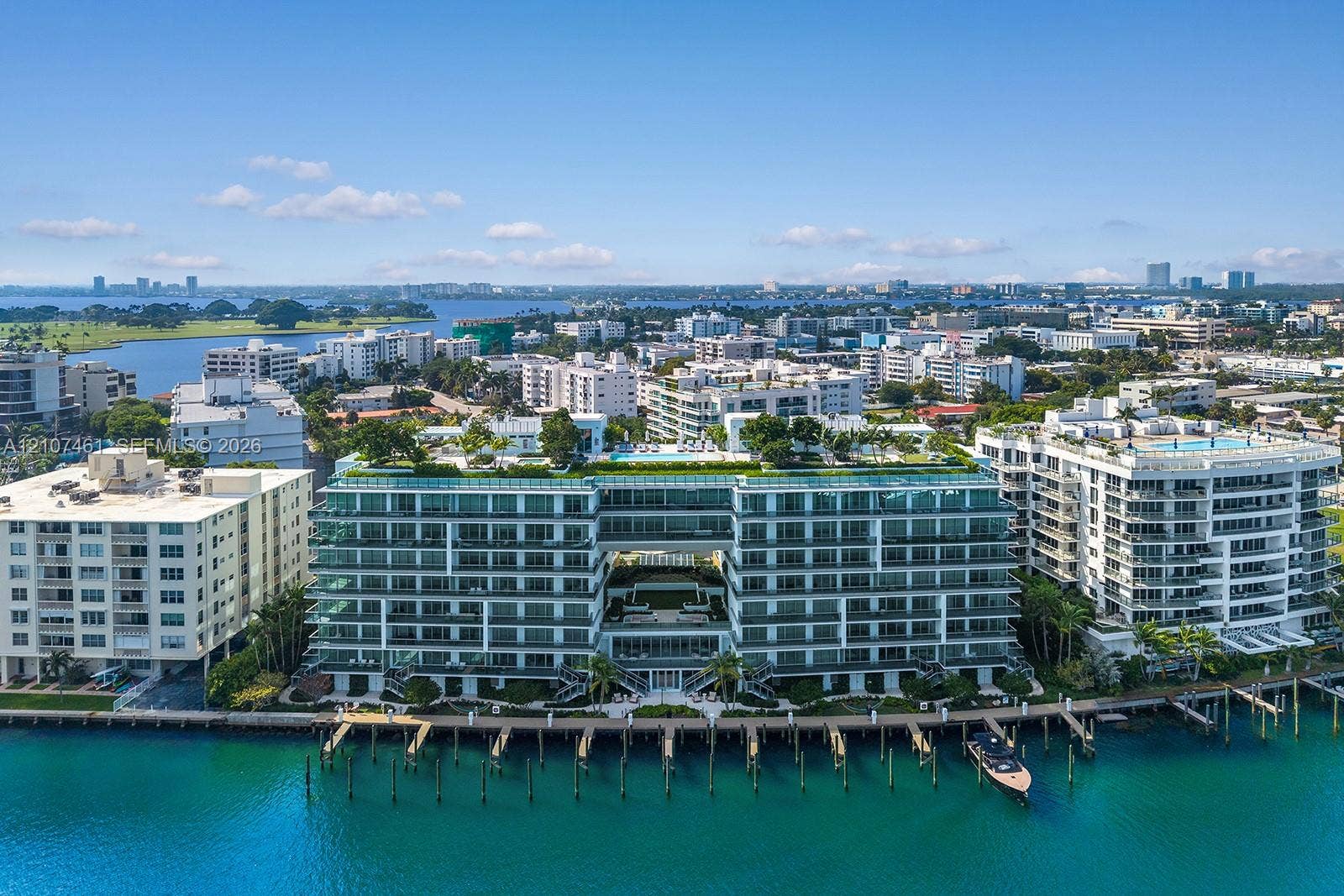 Waterfront mid-rise building featuring a glass-railed rooftop terrace, integrated pool deck, private boat slips, and floor-to-ceiling windows