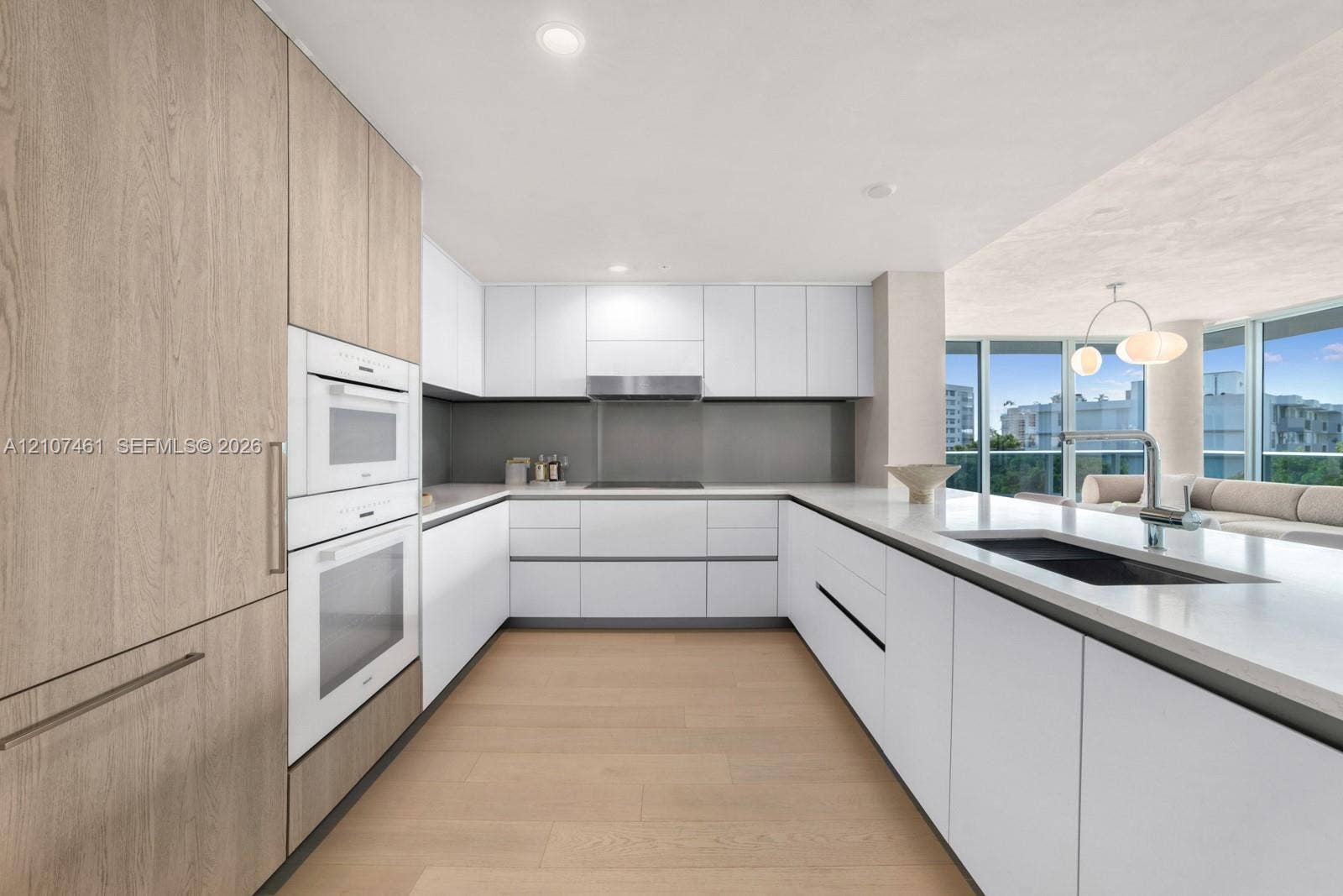 9201 E Bay Harbor Drive, #602, Bal Harbour, FL 33141 Kitchen featuring custom cabinetry, integrated double wall ovens, solid-surface countertops, floor-to-ceiling windows, and wood-finish flooring