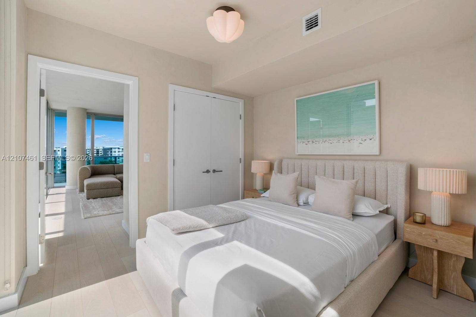 Light-toned wood-finish flooring, white double-door closet with modern hardware, and decorative petal-shaped ceiling light fixture