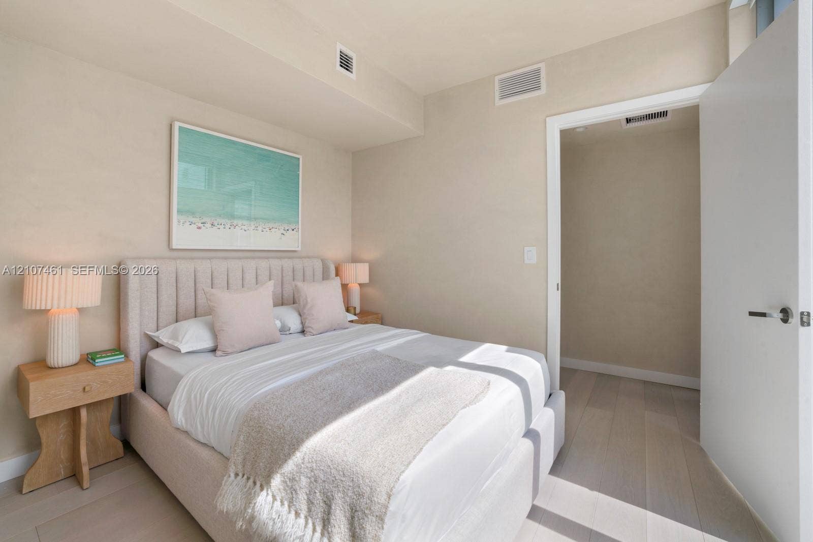 Neutral-toned wall finishes featuring light-finish wood-finish flooring and a minimalist door with brushed metal hardware