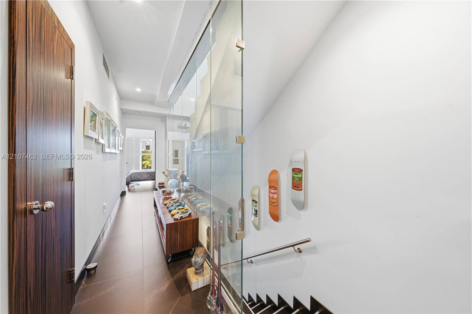 455 NE 39th Street, #110, Miami, FL 33137 Hallway featuring large-format tile flooring, a floor-to-ceiling glass panel wall, and wood-finish door with brushed metallic hardware