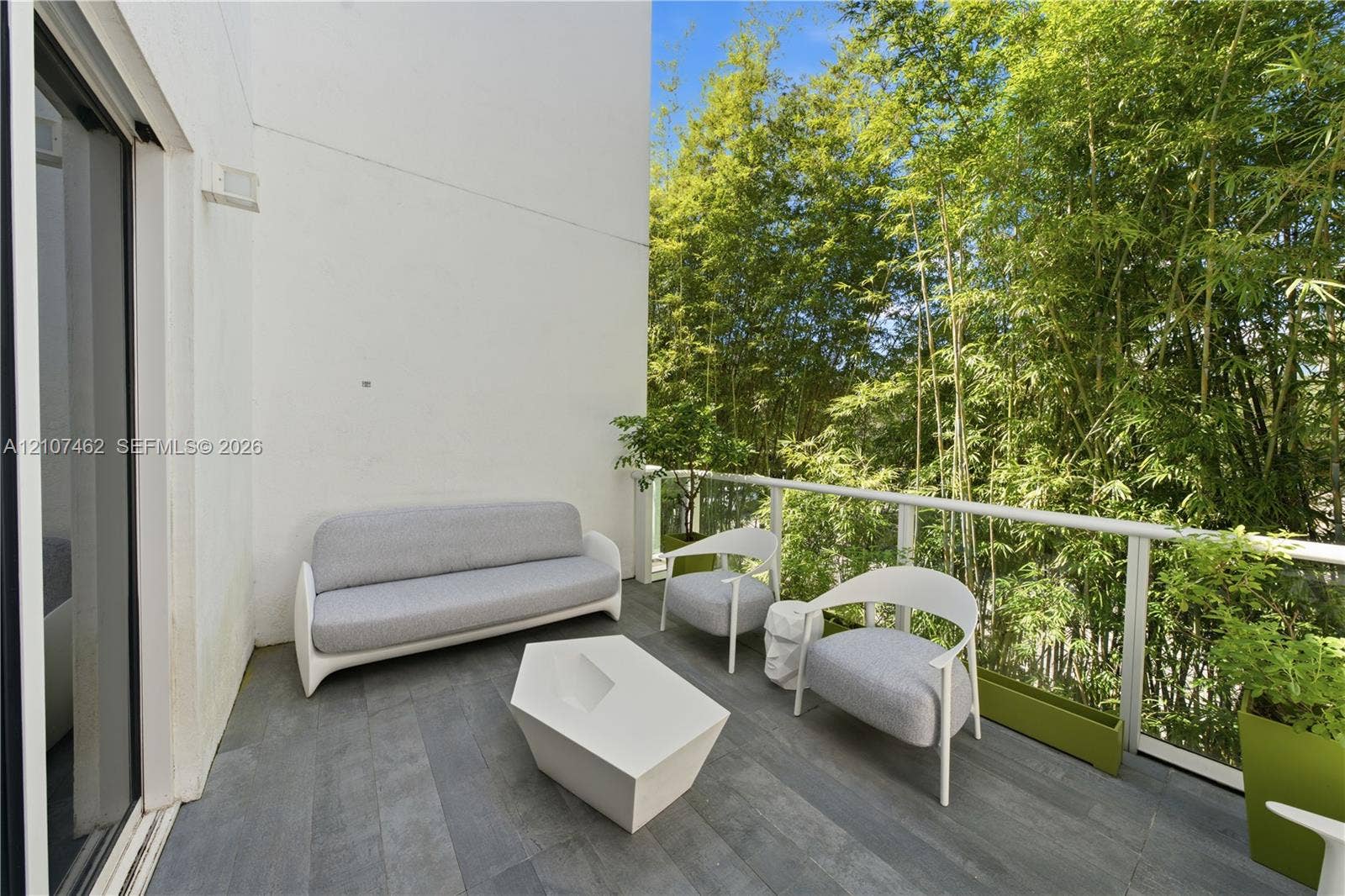 455 NE 39th Street, #110, Miami, FL 33137 Private outdoor balcony featuring wood-finish tile flooring, sleek glass panel railing, and white stucco walls