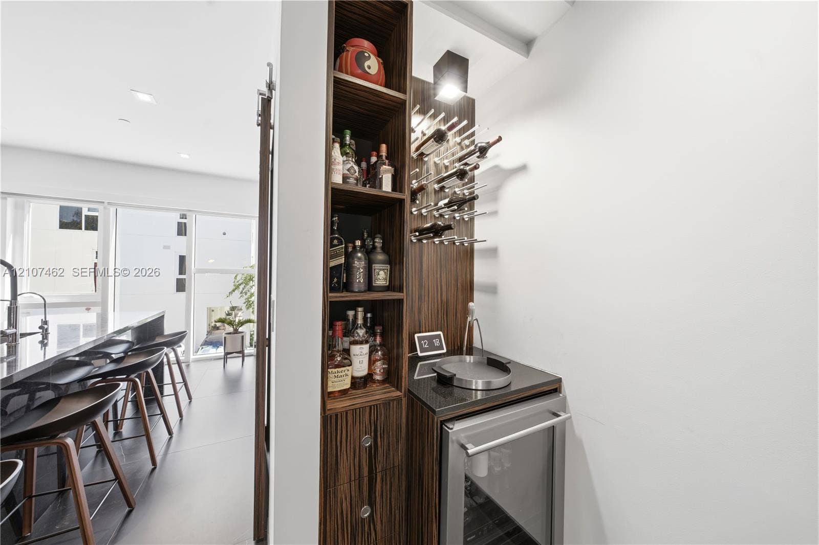 455 NE 39th Street, #110, Miami, FL 33137 Built-in beverage center featuring wood-finish cabinetry, a stone countertop, integrated wine racking, and an under-counter beverage refrigerator