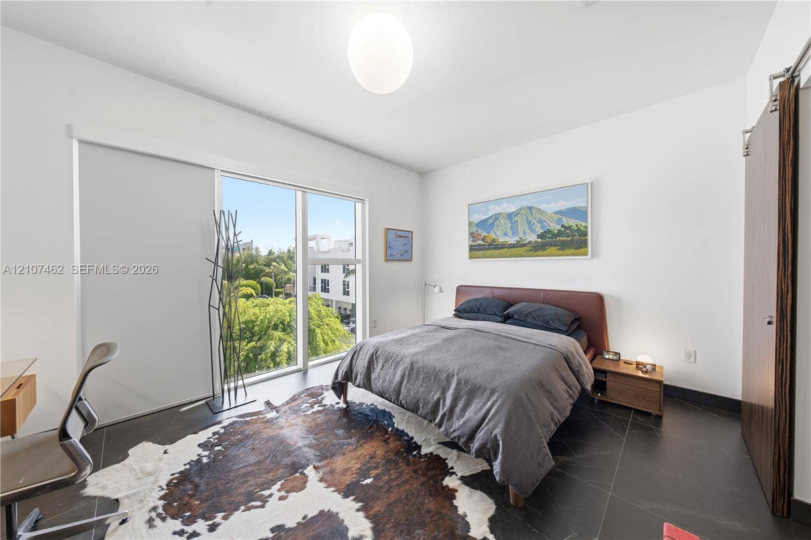 455 NE 39th Street, #110, Miami, FL 33137 Floor-to-ceiling windows featuring mountain scenery, dark large-format tile flooring, and a sliding wood-finish door