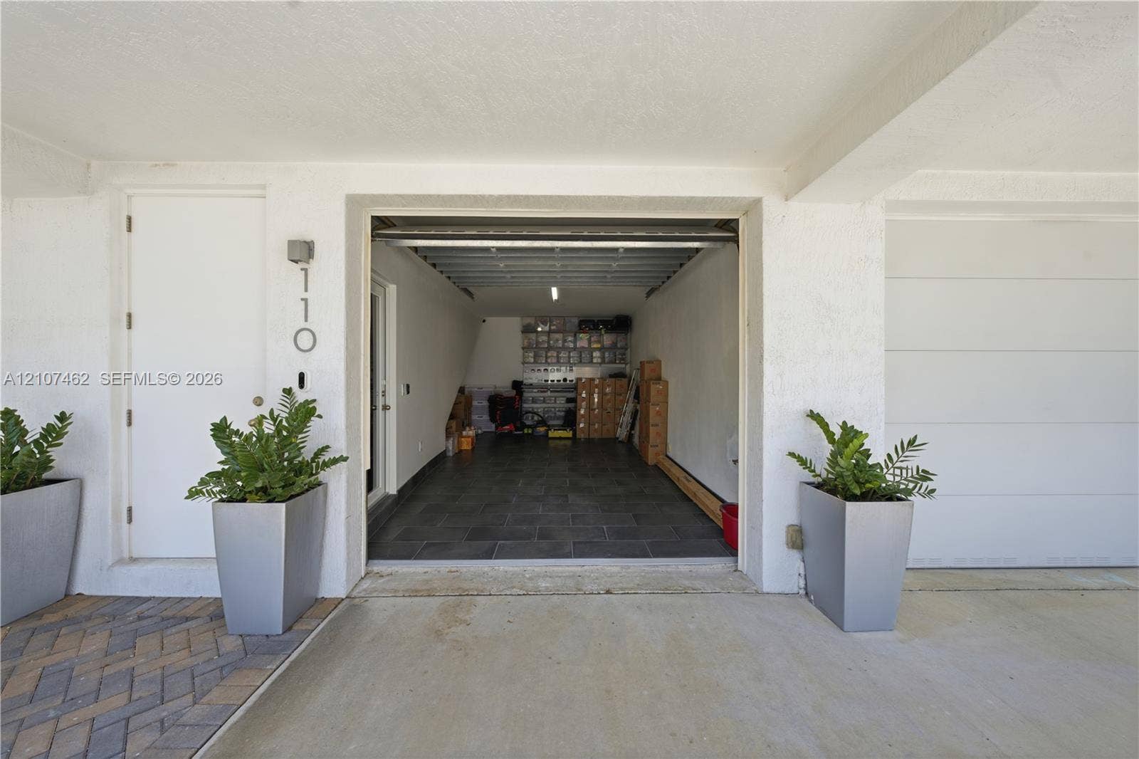 455 NE 39th Street, #110, Miami, FL 33137 Covered parking area featuring stone-tile flooring, white wall finishes, and direct access to an interior entry door