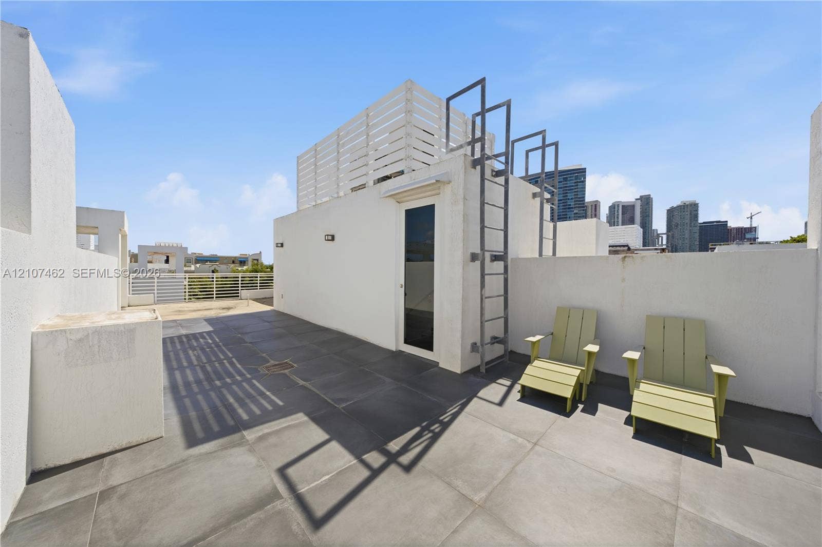 455 NE 39th Street, #110, Miami, FL 33137 Rooftop terrace featuring oversized tile flooring, white stucco privacy walls, a permanent metal ladder, and built-in privacy screening
