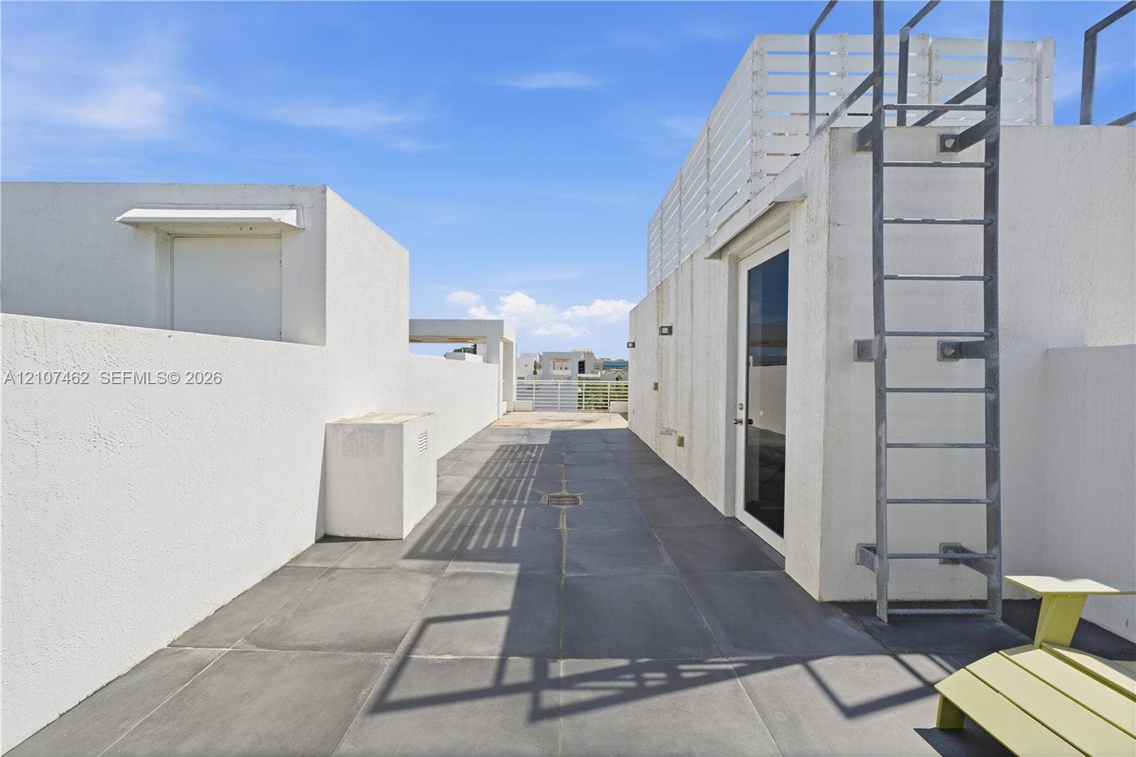 455 NE 39th Street, #110, Miami, FL 33137 Rooftop terrace featuring large-format tile flooring, perimeter privacy walls, integrated exterior wall lighting, and a fixed metal access ladder