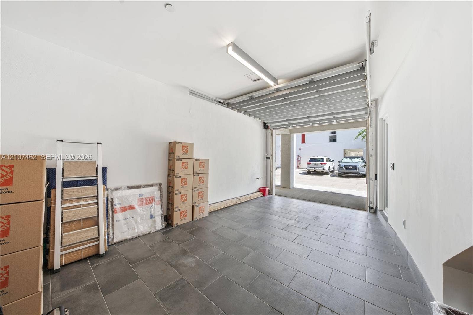 455 NE 39th Street, #110, Miami, FL 33137 Attached garage featuring large-format tile flooring, white walls, and a linear LED light fixture