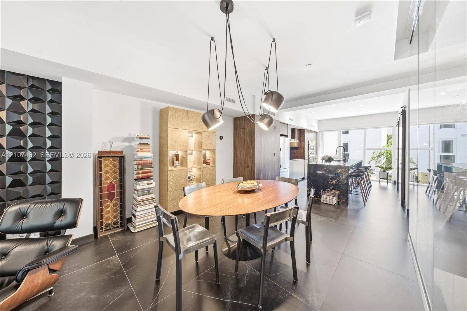 455 NE 39th Street, #110, Miami, FL 33137 Dining area featuring large-format dark floor tile, a sculptural multi-pendant light fixture, a geometric textured accent wall, and integrated floor-to-ceiling cabinetry