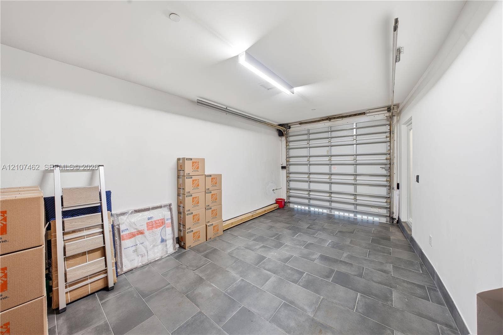 455 NE 39th Street, #110, Miami, FL 33137 Enclosed garage featuring large-format stone-style tile flooring, high-intensity overhead lighting, and a metal sectional door