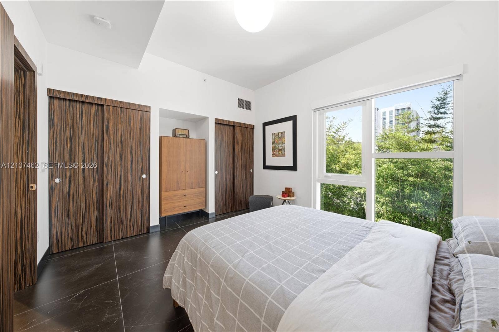 455 NE 39th Street, #110, Miami, FL 33137 Large-format dark tile flooring, dual floor-to-ceiling closets with wood-finish sliding doors, and a expansive window providing natural light
