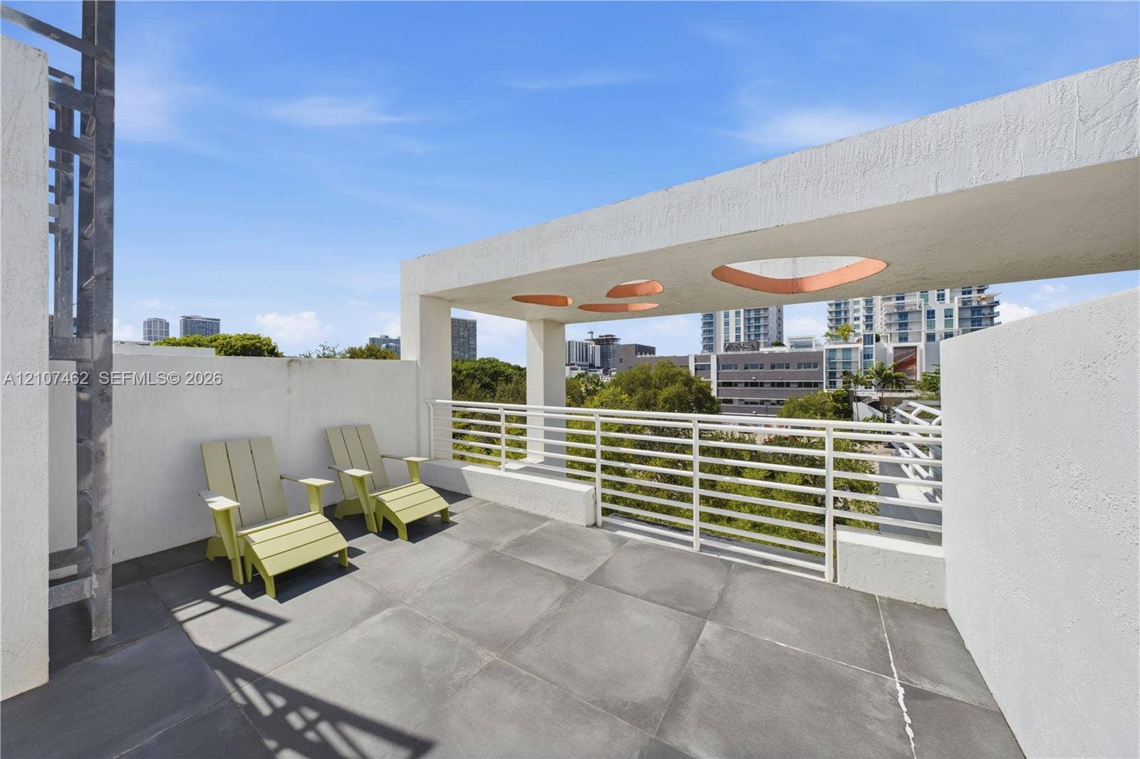 455 NE 39th Street, #110, Miami, FL 33137 Rooftop terrace featuring large-format tile flooring, a white metal railing, and a geometric concrete overhead structure with circular cutouts