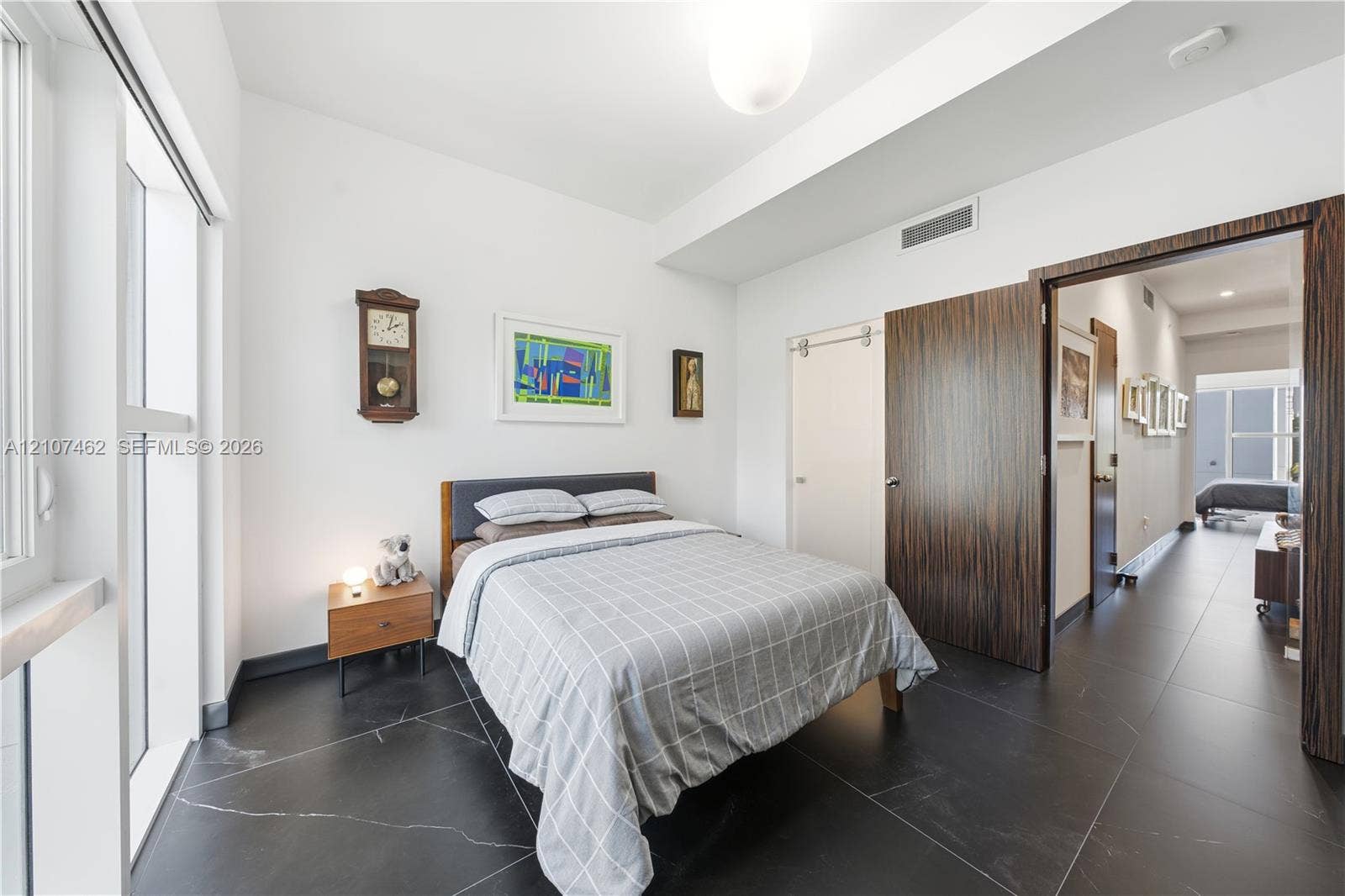 455 NE 39th Street, #110, Miami, FL 33137 Room featuring large-format dark stone tile flooring, high ceilings, full-height windows, a wooden interior door, and a sliding door
