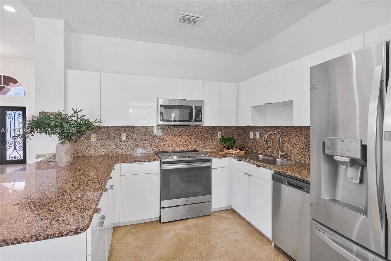 7071 W 6th Avenue, #N/A, Hialeah, Hialeah, FL 33014 Kitchen featuring gloss-finish flat-panel cabinetry, stone-surface countertops with backsplash, stainless steel appliances, and a dual-basin sink with a pull-down faucet