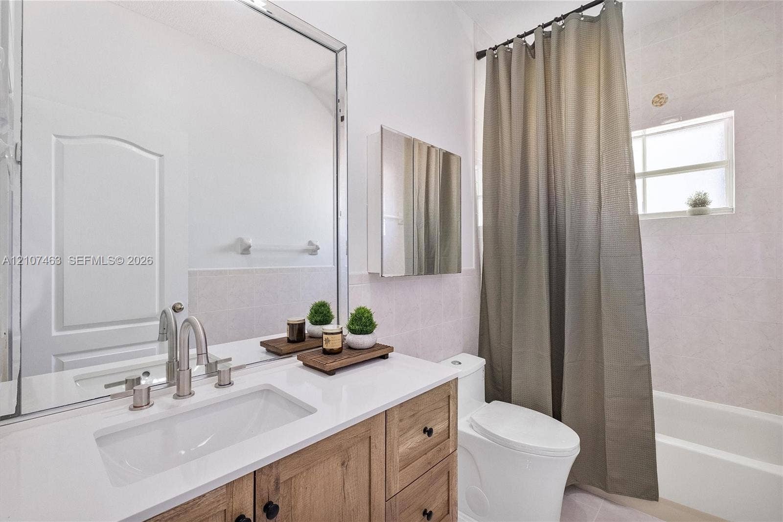 7071 W 6th Avenue, #N/A, Hialeah, Hialeah, FL 33014 Bathroom 1 featuring a wood-finish vanity with a white countertop, an undermount sink, brushed nickel hardware, and a large wall-mounted mirror