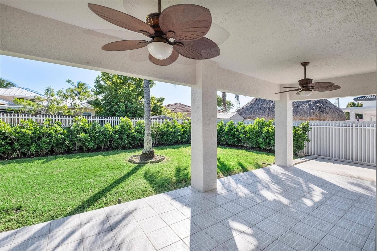 7071 W 6th Avenue, #N/A, Hialeah, Hialeah, FL 33014 Covered patio featuring ceramic tile flooring, twin ceiling fans with light fixtures, and structural support columns