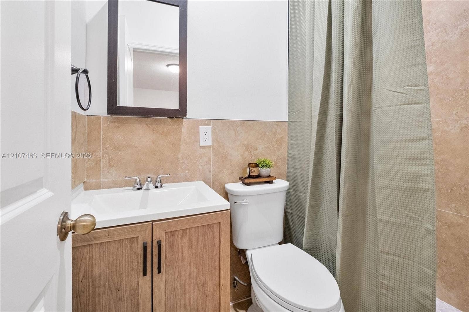 7071 W 6th Avenue, #N/A, Hialeah, Hialeah, FL 33014 Bathroom 2 featuring a wood-finish vanity with a rectangular sink, chrome widespread faucet, wall-mounted medicine cabinet, and neutral-toned wall tiling