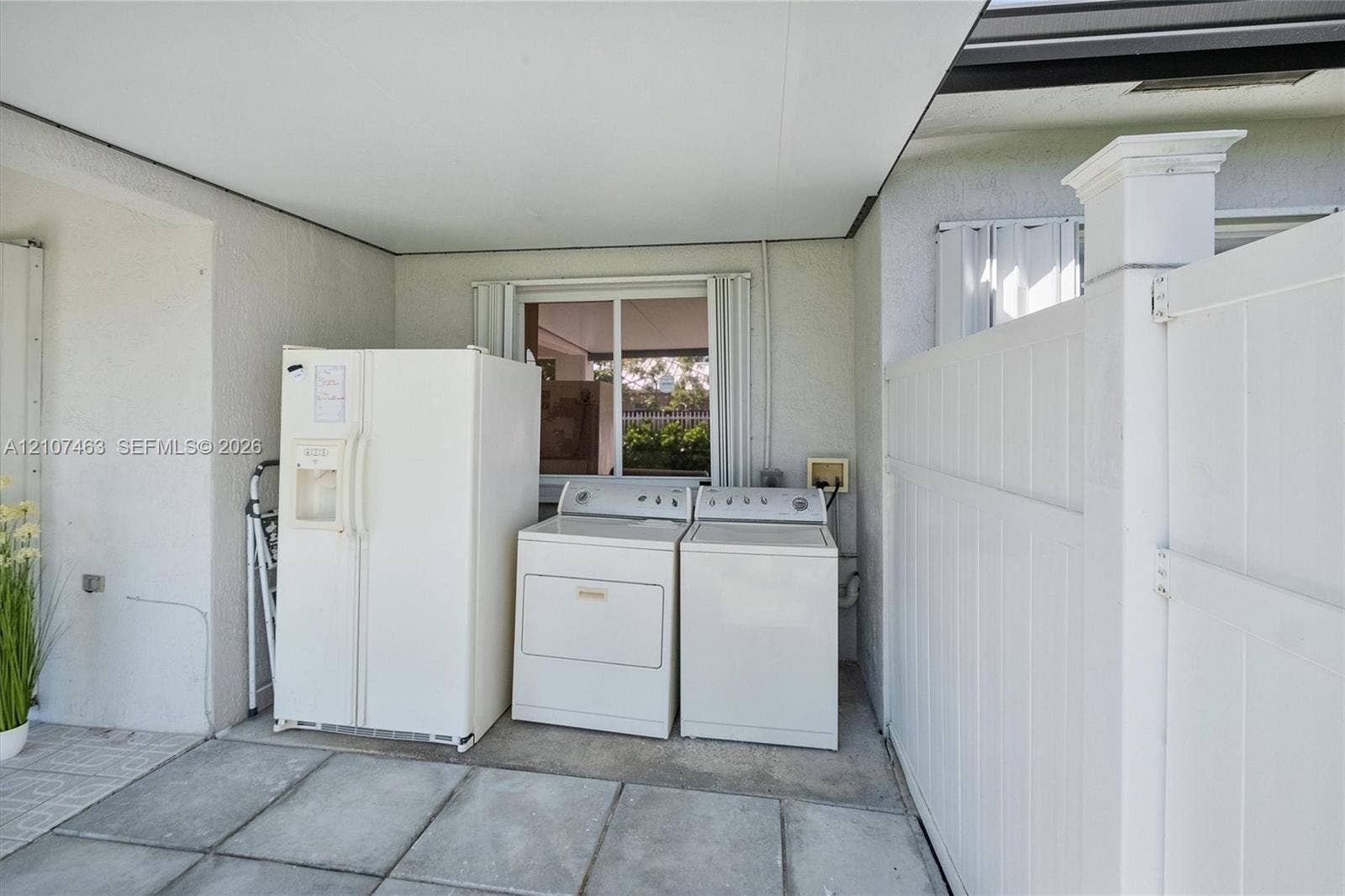 7071 W 6th Avenue, #N/A, Hialeah, Hialeah, FL 33014 Covered concrete patio featuring laundry area and white vinyl privacy fencing
