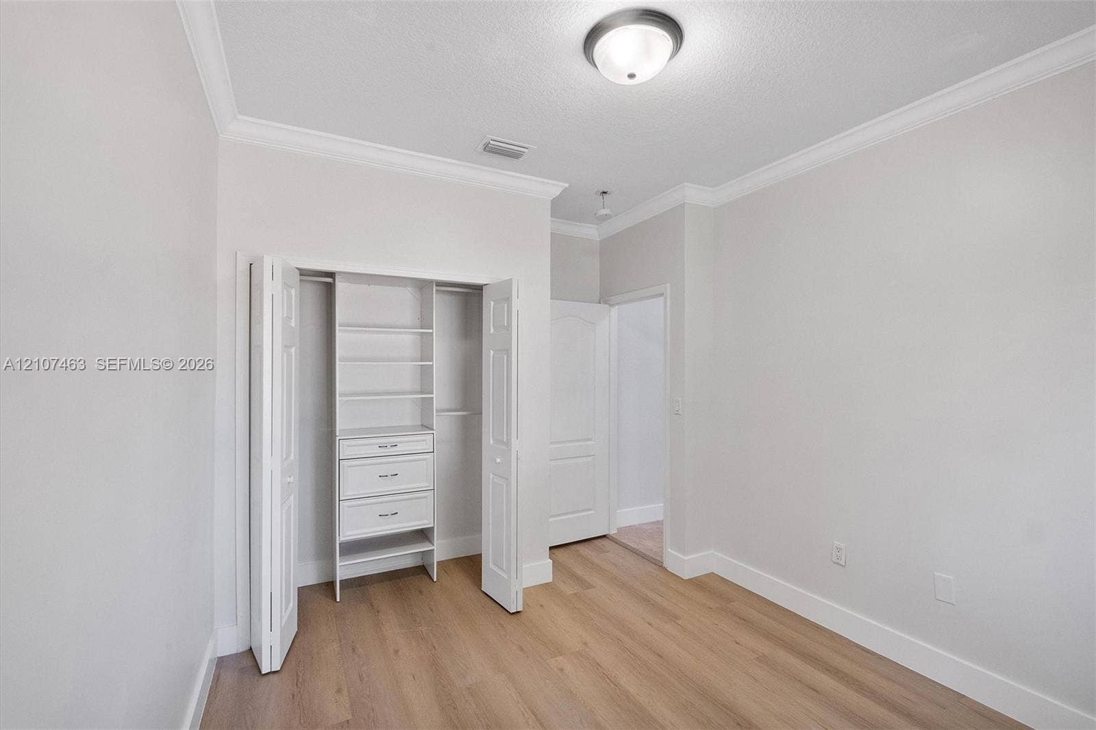 7071 W 6th Avenue, #N/A, Hialeah, Hialeah, FL 33014 Room 2 Closet with wood-finish flooring, crown molding, flush-mount ceiling lighting, and a closet featuring built-in shelving and drawers