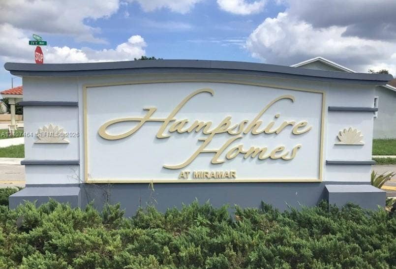 9721 W Daffodil Lane, Miramar, FL 33025 Community monument sign featuring stucco construction, dimensional lettering, and decorative molding details surrounded by low-profile landscaping