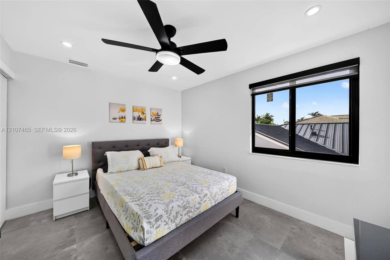 Large-format tile flooring, recessed ceiling lighting, matte black ceiling fan, and window with black frame