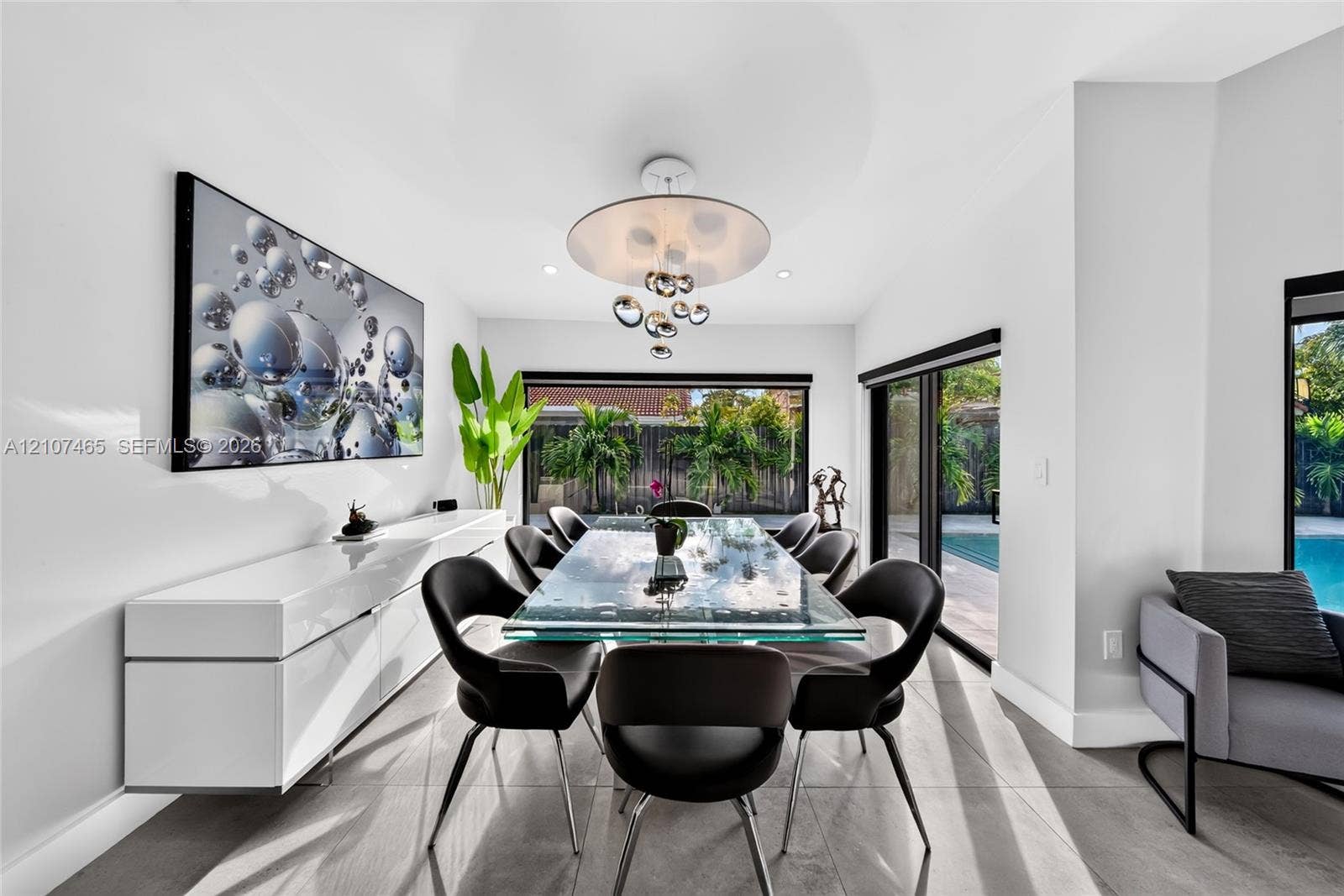 Dining space featuring large-format tile flooring, a modern multi-pendant light fixture, and black-framed sliding glass doors
