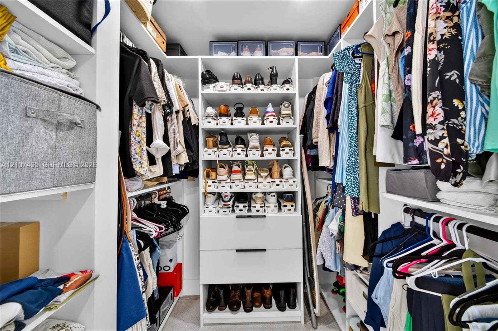 Walk-in closet featuring white built-in shelving, integrated shoe storage, and two soft-close drawers with matte black hardware