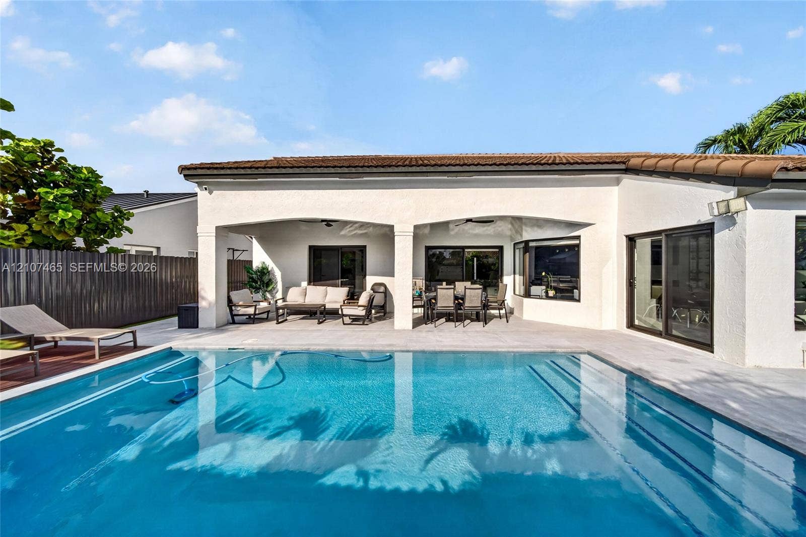 Rear exterior featuring a covered patio, rectangular swimming pool with built-in steps, tile roofing, and sliding glass door access