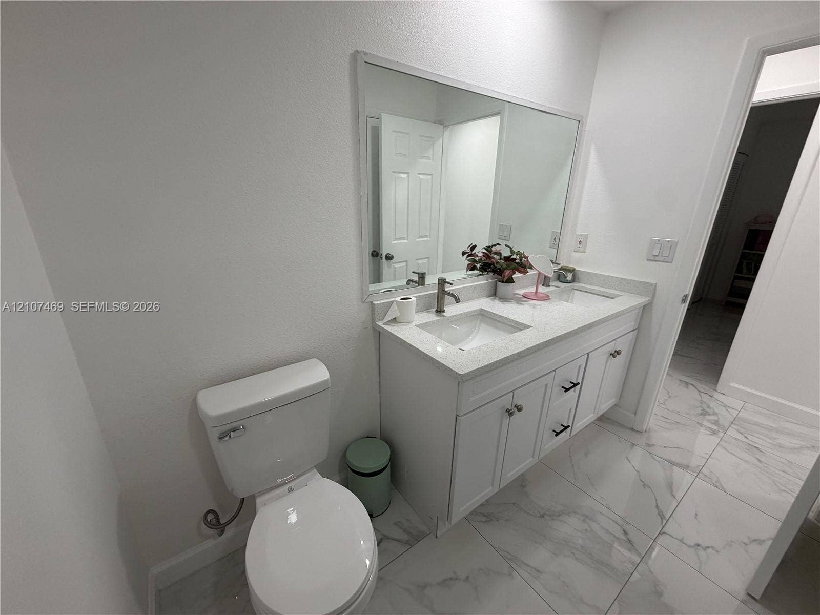 Double vanity featuring white cabinetry, stone-finish countertops, dual integrated sinks, and large-format tile flooring