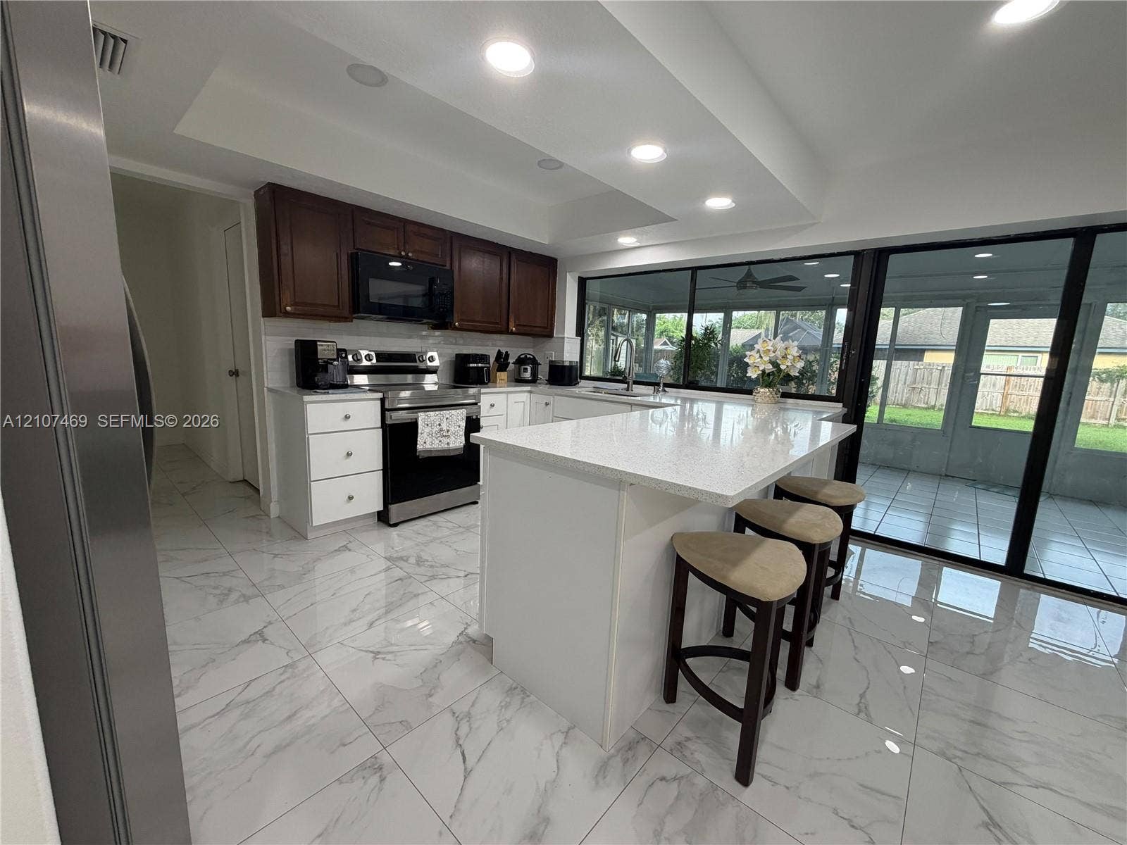 Kitchen featuring stone-surface countertops, central island, dual-tone cabinetry, recessed lighting, and large-format tile flooring