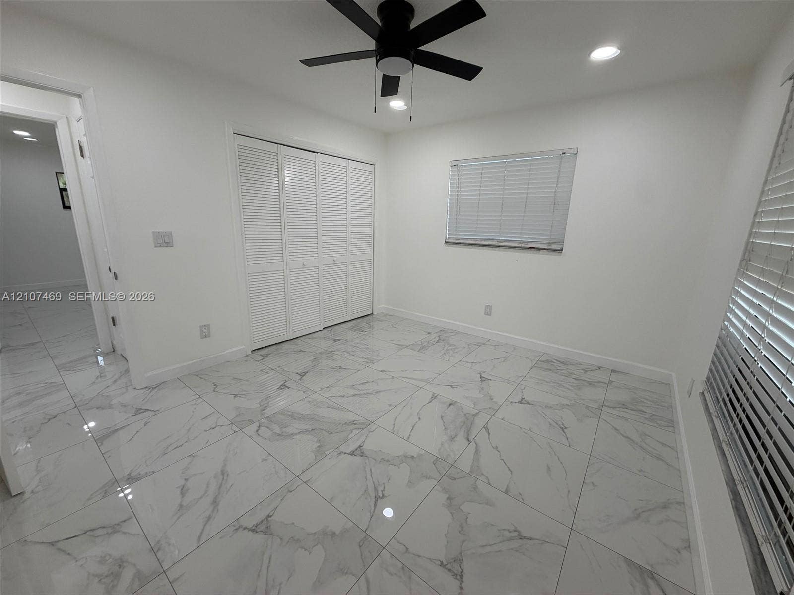 Large-format tile flooring with a veined finish, recessed lighting, ceiling fan with integrated lighting, louvered closet doors, and windows featuring horizontal blinds