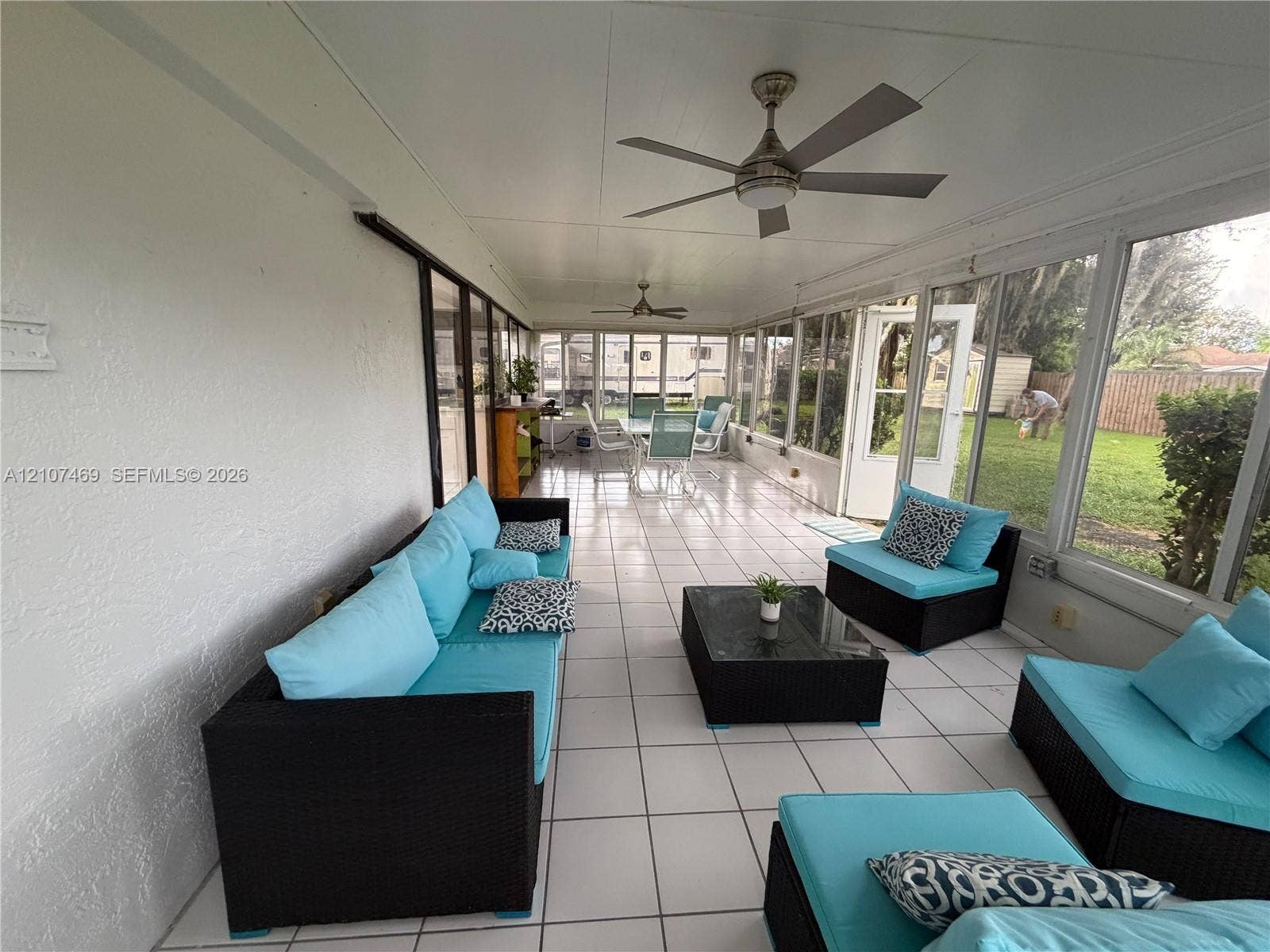 Enclosed patio featuring tile flooring, ceiling fans, and expansive floor-to-ceiling windows